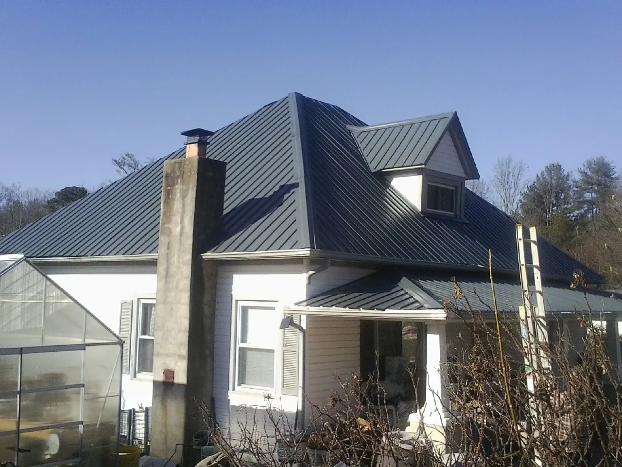 Dark blue standing seam metal roof on a white farmhouse with dormer — Slate & Tile Roof Repair by Roofing Brothers in East Wenatchee