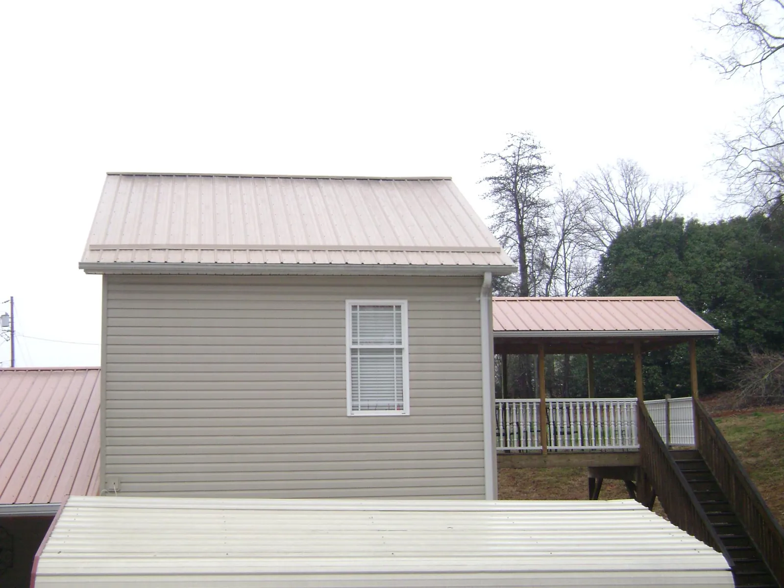 Tan metal roofs on a two story addition and attached porch, from a Roof Replacement job in East Wenatchee