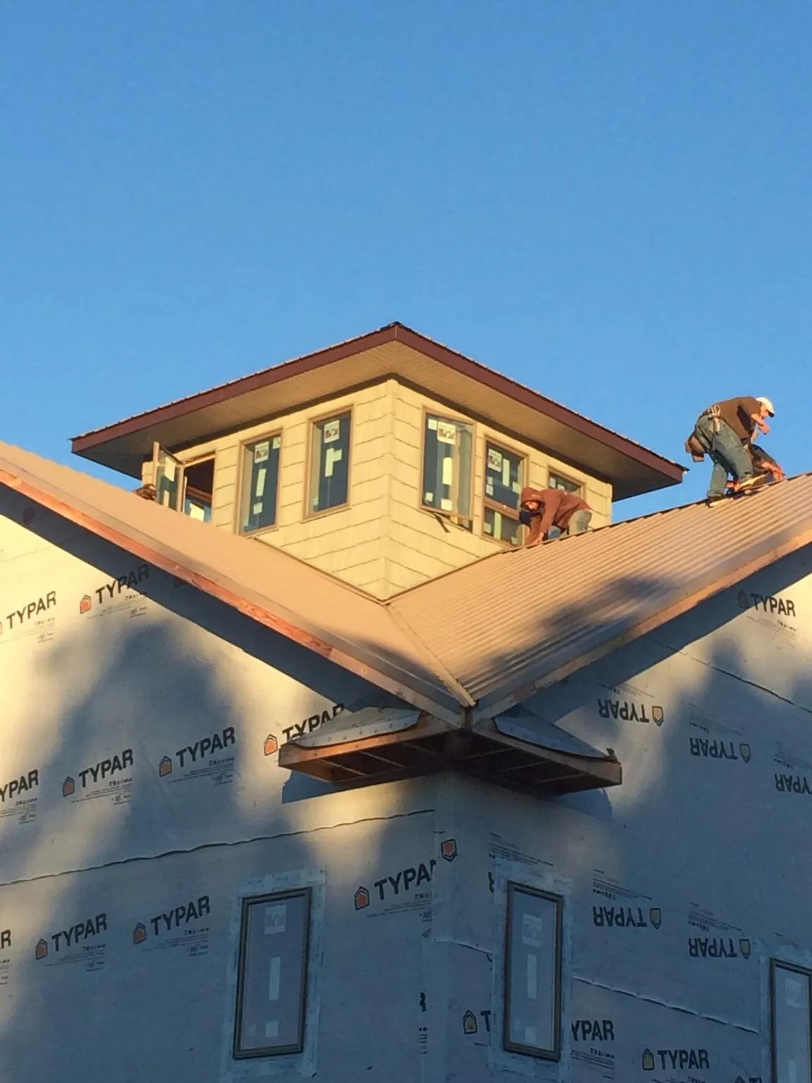 Roofers working around a rooftop cupola on a new metal roof at sunset — Roof Waterproofing in East Wenatchee by Roofing Brothers